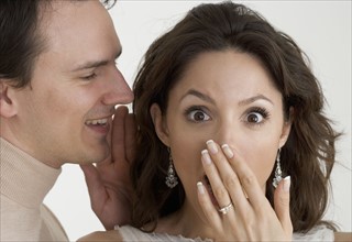 Man telling woman a surprising secret.