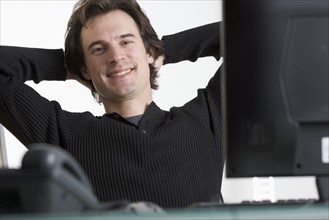 Smiling man at desk with computer.