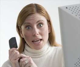 Annoyed woman with phone and computer.