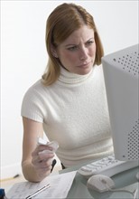 Distressed woman at desk with computer.