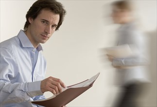 Man holding file with person passing.