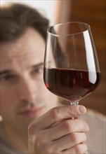 Man examining upheld glass of wine.