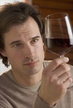 Closeup of man examining red wine.