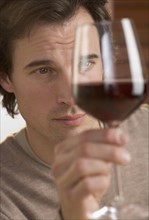 Closeup of man scrutinizing red wine.