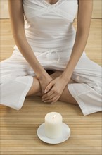 Cross-legged woman's torso with candle.