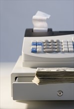 Cash register with pile of cash.