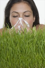 Woman blowing nose with grass.