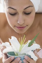 Woman with towel smelling flower.