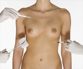 Nude female torso with medical instruments.