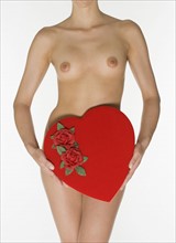 Nude female holding heart shaped box.