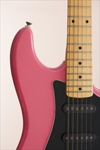 Closeup of pink electric guitar.