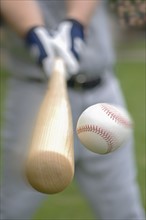 Closeup of baseball player hitting ball.