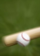 Closeup of bat hitting baseball.