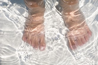 Child's feet standing in water.
