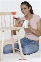 Woman painting wooden chair.