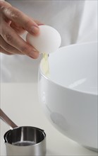 Hand cracking egg into bowl.
