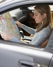 Woman in car looking at a map.
