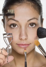 Woman's face with many cosmetic tools.
