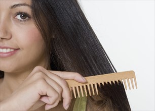 Woman combing hair with wooden comb.