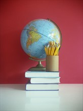 Still life of books, pencils, and globe.
