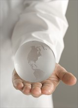 Glass globe held in outstretched hand.