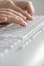 Closeup of hands typing on keyboard.
