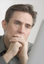 Businessman looking thoughtfully at computer monitor.