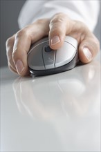 Hand on computer mouse with reflection.