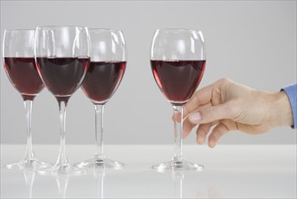 Hand reaching for glass of wine.