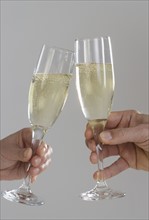 Profile of hands toasting champagne flutes.