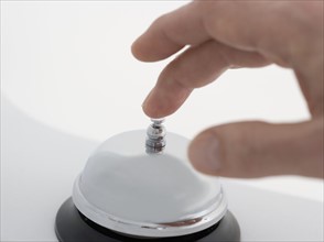 Closeup of hand ringing desk bell.