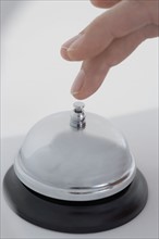 Closeup of finger ringing desk bell.