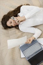 Businesswoman on mobile phone while lying on bed.