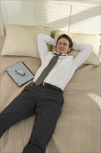 Businessman lying on bed with laptop.