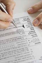 Closeup of hands signing tax form.