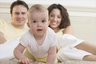 Baby crawling on bed with parents.