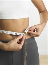 Closeup of woman measuring her waist.