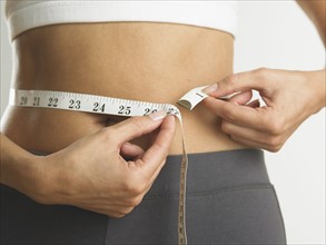 Closeup of woman measuring her waist.
