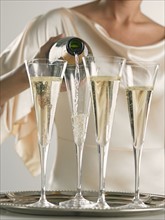 Woman pouring champagne into flutes.
