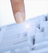 Finger pushing enter key on computer.