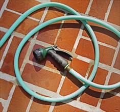 Closeup of garden hose and brick floor.