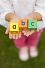 Closeup of girl holding alphabet blocks.