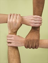Hands holding arms in multiracial group.