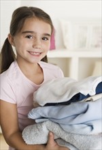 Young girl holding laundry.