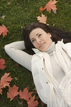 Woman lying on grass on fall day.
