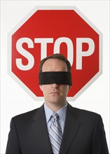 Man wearing blindfold at stop sign.