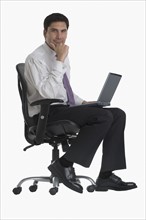 Businessman holding laptop in chair.