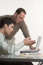 Two men conferring at computer.