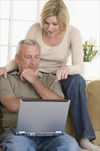 Couple using laptop computer at home.