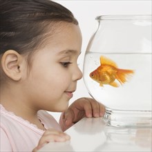Young girl watching a fishbowl.